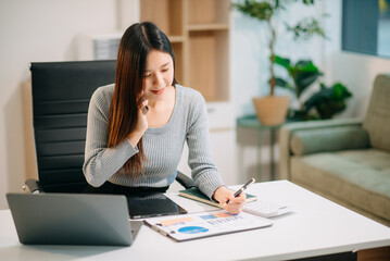 Asian business woman typing laptop and tablet Placed at the table at the office