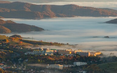 Autumn landscape with a small town, residential houses, fog in the valley and hills. Colorful...
