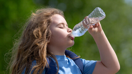 Thirsty child drinking water from bottle. Kid refreshing with drink. Thirsty child drink water from...