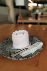 A delightful pink mini-cake sits on a speckled plate, adding a sweet touch to a bright and airy...