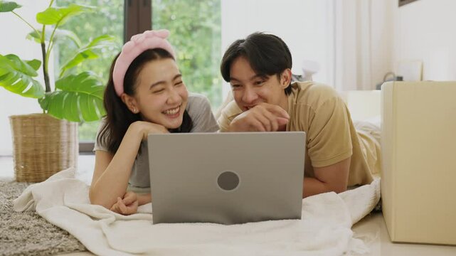 Asian couple planning with laptop computer indoors at home, relocation and home decoration concept.