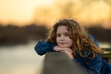 Fotobehang Dreamy little. Relaxed child feeling the breeze in the park. Thoughtful expression on a child face. Future thinker enjoying a quiet day. Portrait of a peaceful child. Cute child exploring imagination. © Volodymyr