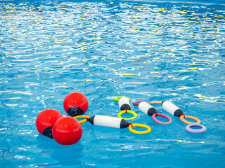 Colorful dolphin training toys, red buoys and multi colors rings, floating on the water pool. Holiday and vacation, summer fun show concept.