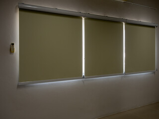 Closed roller blinds, three white curtain or white blinds Roller, sun protection in the dark room, office or meeting room background with nobody.