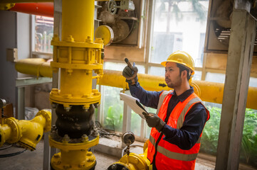 An engineer is checking the pressure valve of a gas pipeline and recording the pressure readings