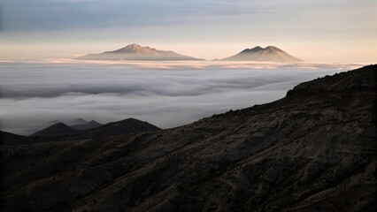 Mountain peaks rise above a sea of clouds at dawn, creating a stunning landscape.