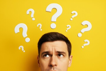Confused man surrounded by floating question marks on bright yellow background, symbolizing uncertainty and decision-making in business context.