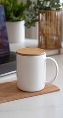 White mug with light brown lid on a wooden coaster, beside laptop and plants