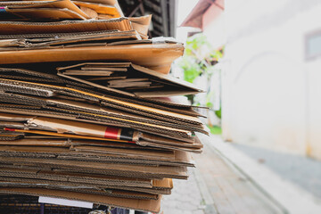 Cardboard waste pile stacked in front of convenience store prepared for reuse. Recycle concept.