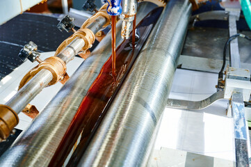 Glue-spreading machine meticulously applies adhesive on a smooth surface in a bustling...