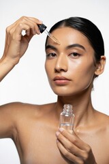 Woman Applying Serum with Dropper in Studio Setting
