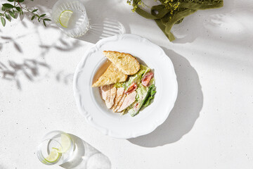 Chicken caesar salad plated, bright natural lighting, overhead minimal composition