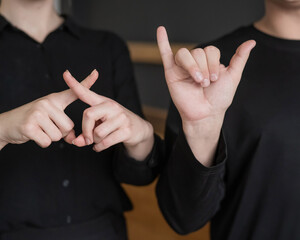 A man and a woman show the phrase technical university in sign language. 