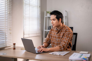 A man is sitting at a desk with a laptop in front of him