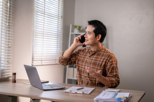 A man is talking on his cell phone while sitting at a desk