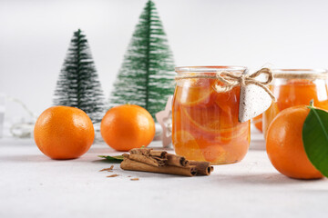 Homemade tangerines jam with orange peel in a glass jar as a gift for Christmas or New year, spices. Selective focus.