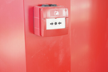 Fire alarm box mounted on a bright red wall indoors
