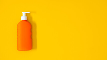 Orange bottle of sunscreen on bright yellow background. Sun protection. UV protection. Summer. Top view