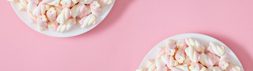 Panoramic background of marshmallows in white plates. Texture of multicolored sweet marshmallows on a plate. Marshmallow candies for background. Banner