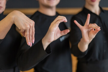A man and two women demonstrate a phrase in sign language. 