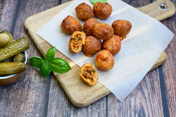 Mini cheese  burger balls.  Ball shaped snack with meat, pickled cucumbers and tomato on wooden...