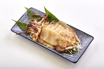 Grilled squid served on decorative plate with garnish of green leaves, showcasing tender slices and...