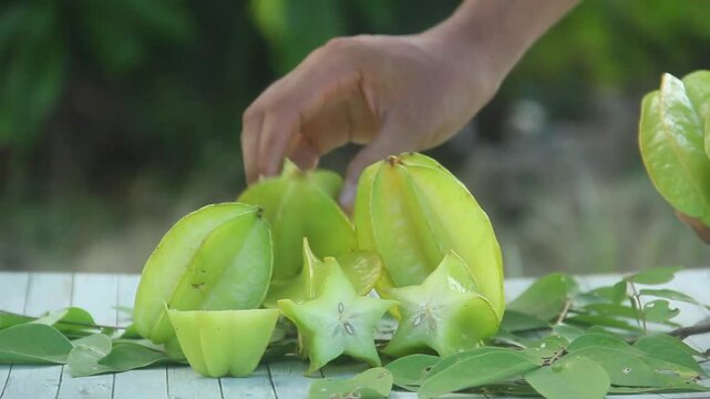 A man slicing fresh Averrhoa carambola or star fruit arranged on an outdoor table