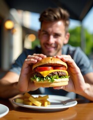 Happy customer showing delicious cheeseburger with french fries at restaurant