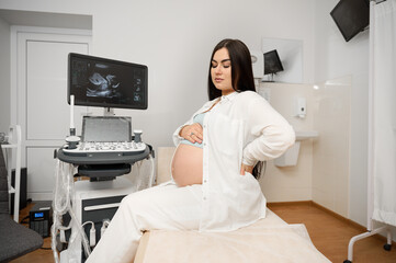 Pregnant woman sitting in medical office waiting for examination. Pregnancy. Fetal care. Check up...
