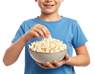 A child wearing a blue shirt is holding a bowl filled with popcorn and reaching in to grab some.
