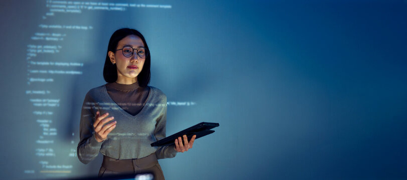 asian woman programmer standing in front of a screen with code projected  presentation the integration of technology and human expertise in software development