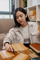 an entrepreneur is packing parcel for order from customer, she own a small business, sme, a lot of...