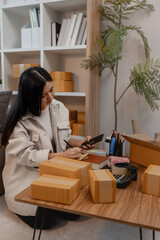 an entrepreneur is packing parcel for order from customer, she own a small business, sme, a lot of...
