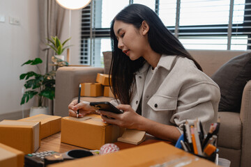 an entrepreneur is packing parcel for order from customer, she own a small business, sme, a lot of package in the room, e-business is running by a this entrepreneur, online shopping