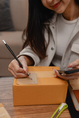 an entrepreneur is packing parcel for order from customer, she own a small business, sme, a lot of package in the room, e-business is running by a this entrepreneur, online shopping