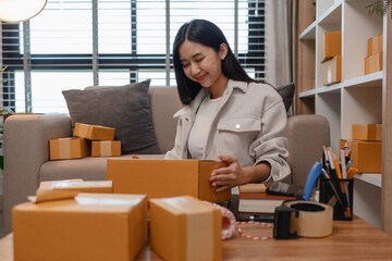 she is packing parcel to send to all customers, this entrepreneur own a small business, sme, selling product online, she prepare her product in her office, packing order
