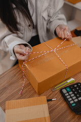 she is packing parcel to send to all customers, this entrepreneur own a small business, sme, selling product online, she prepare her product in her office, packing order