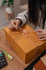 she is packing parcel to send to all customers, this entrepreneur own a small business, sme, selling product online, she prepare her product in her office, packing order
