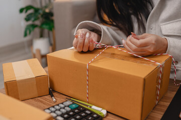 she is packing parcel to send to all customers, this entrepreneur own a small business, sme, selling product online, she prepare her product in her office, packing order