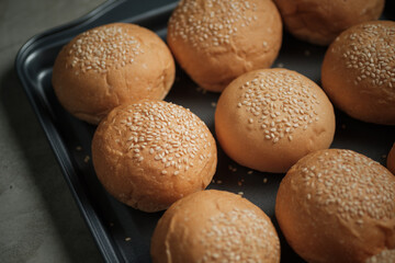 top view shot of a part of oven tray full with sesame burger buns put on rusty kitchen table with...