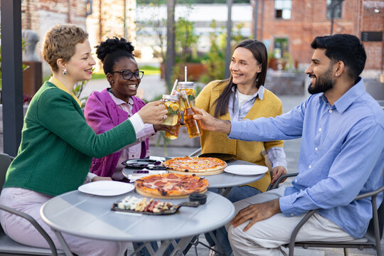 Group of friends enjoying a meal together outdoors, clinking glasses in a celebratory toast.