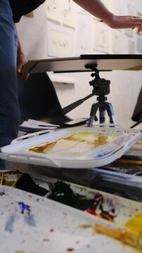 Professional fixes sheet on special stand before work. Artist prepares to begin work and arranges spacious workspace standing in front of drawings