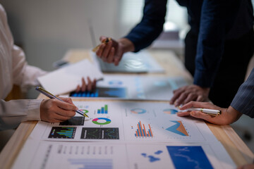 A group of people are looking at a table with graphs and charts