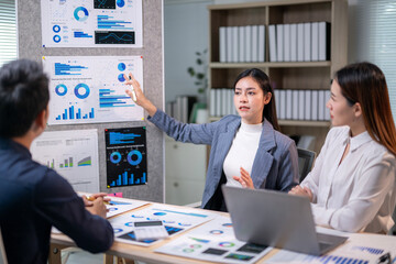 Three people are sitting at a table with a presentation on a wall behind them