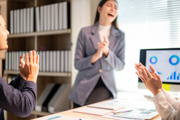 A woman is standing in front of a computer monitor and clapping