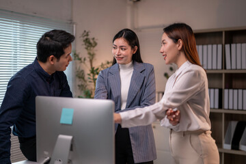 Three people are standing in front of a computer monitor