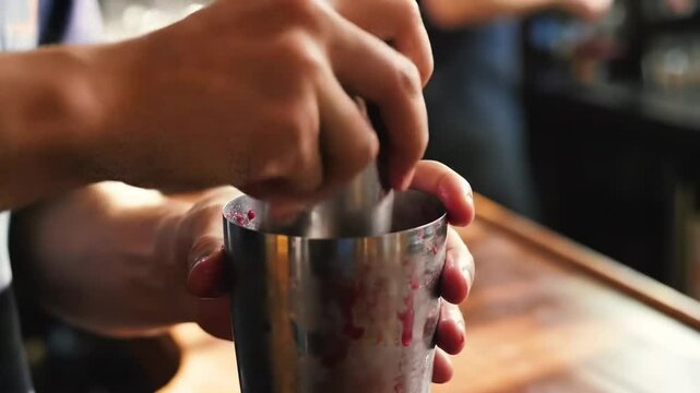 Bartender crafting a delicious cocktail with metal muddler and mixing glass