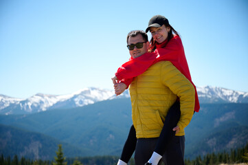 Two hikers taking a break on a mountain ridge. Sporty couple with hiking backpacks standing on...