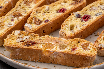 Italian Almond Biscotti biscuits in a rustic home made pottery bowl. Studded with almonds and cranberries, these twice-baked treats are aromatic and inviting. Ideal.