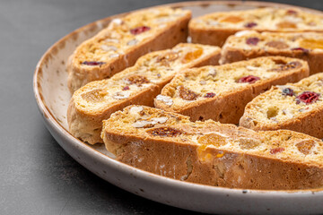 Italian Almond Biscotti biscuits in a rustic home made pottery bowl. Studded with almonds and cranberries, these twice-baked treats are aromatic and inviting. Ideal.